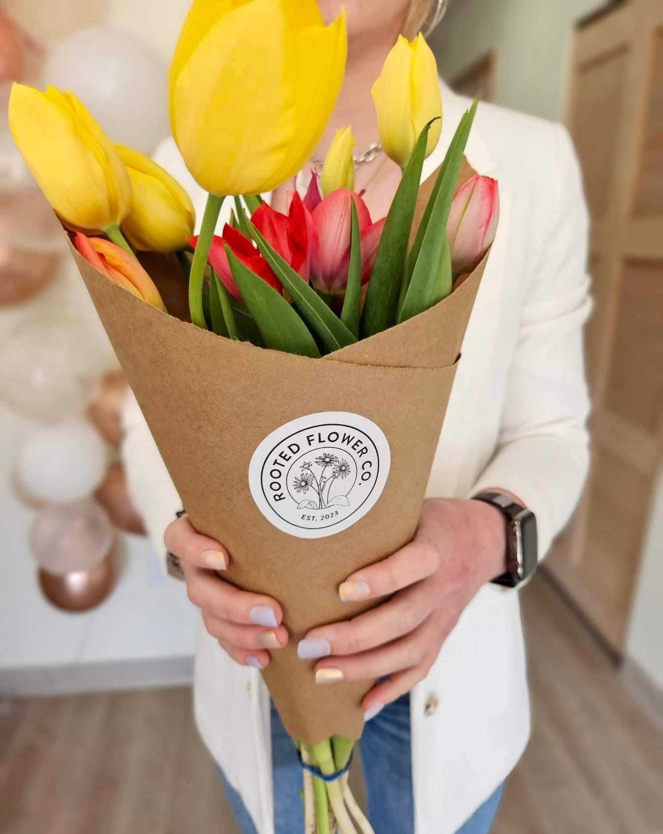 Bouquet of tulips wrapped in brown paper and Rooted Flower Co. sticker